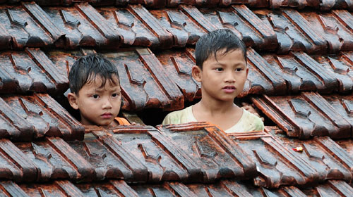Ảnh Hai anh em nhỏ dỡ ngói để vẫy lực lượng cứu hộ tại xã Đức Hương, Vũ Quang, Hà Tĩnh. Ảnh: Tuổi trẻ TP.HCM/Tuổi trẻ Online